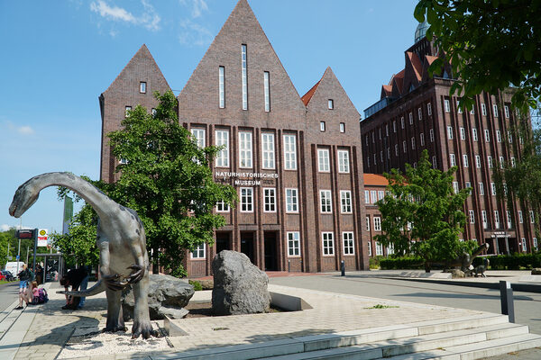 Außenansicht des Naturhistorischen Museums mit Dinosaurier-Plastik im Vordergrund (Zoom on click)