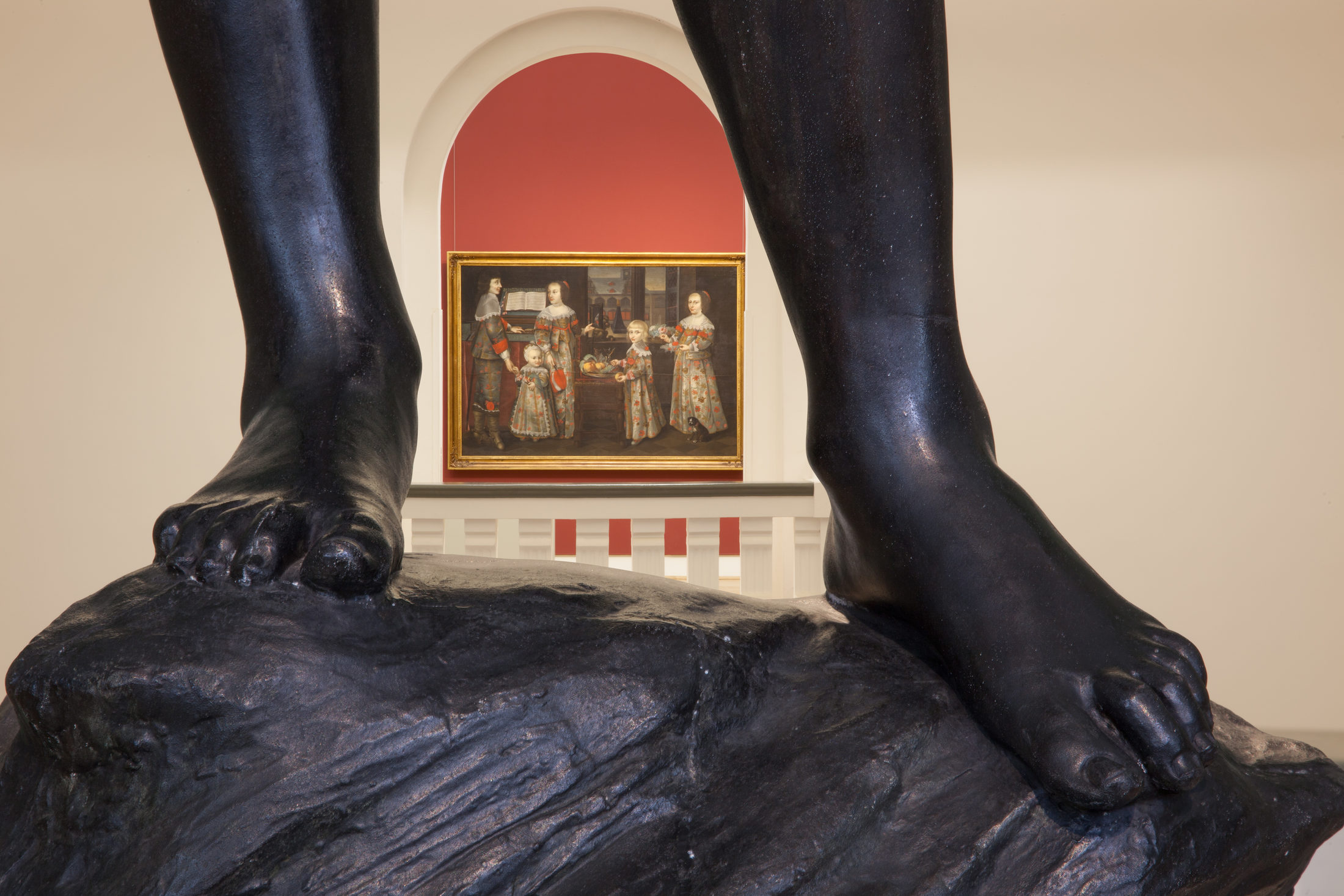 Einblick in die Ausstellungsräume des Hauses am Löwenwall mit Gemälde im Hintergrund und ausschnitthaft die schwarzen Füße einer Skulptur im Vordergrund.