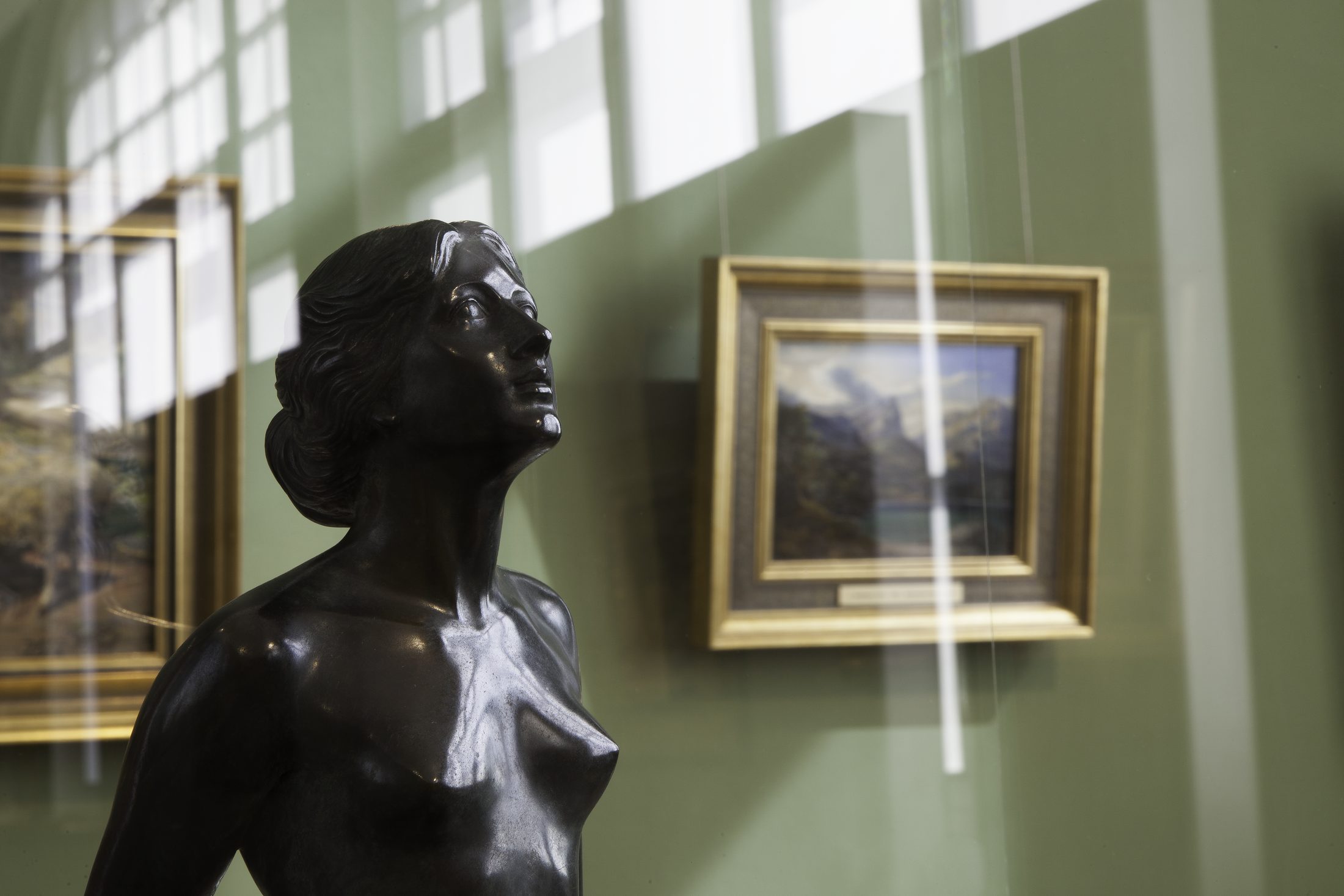 Blick in einen Ausstellungsraum im Haus am Löwenwall (im Vordergrund eine Skulptur, im Hintergrund Gemälde) (Wird bei Klick vergrößert)