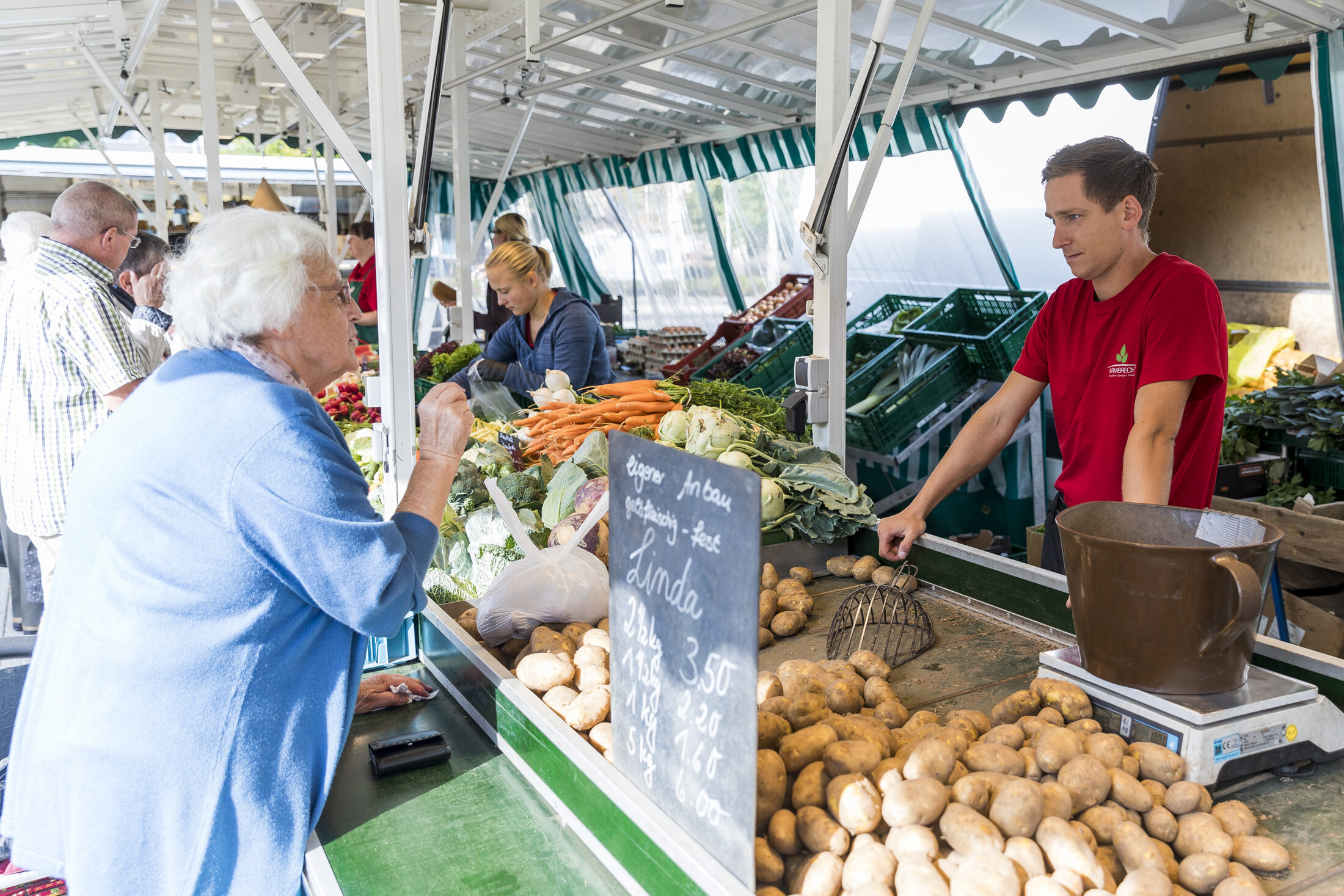 Kunden beim Einkaufen an einem Marktstand (Wird bei Klick vergrößert)