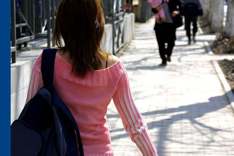 Rückenansicht einer Frau, die eine Straße entlanggeht