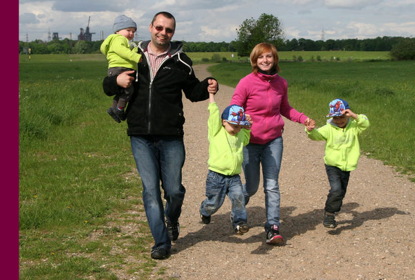 Eltern gehen mit drei Kindern spazieren