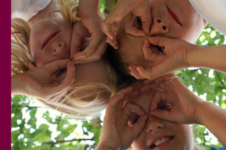 Drei Kinder blicken durch ihre Finger in die Kamera