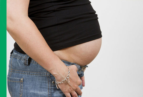Eine schwangere Frau (nur der Bauch zu sehen)