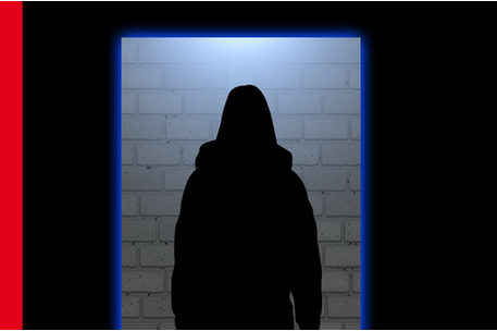 Silhouette einer Frau in einem Rahmen vor einer diffus beleuchteten Mauer