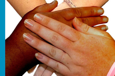 Hände unterschiedlicher Hautfarbe, die aufeinanderliegen
