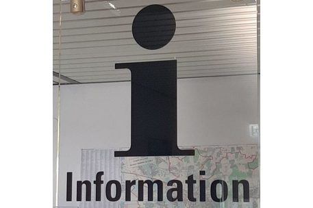 transparentes Schild "Information" mit einem Stadtplan im Hintergrund