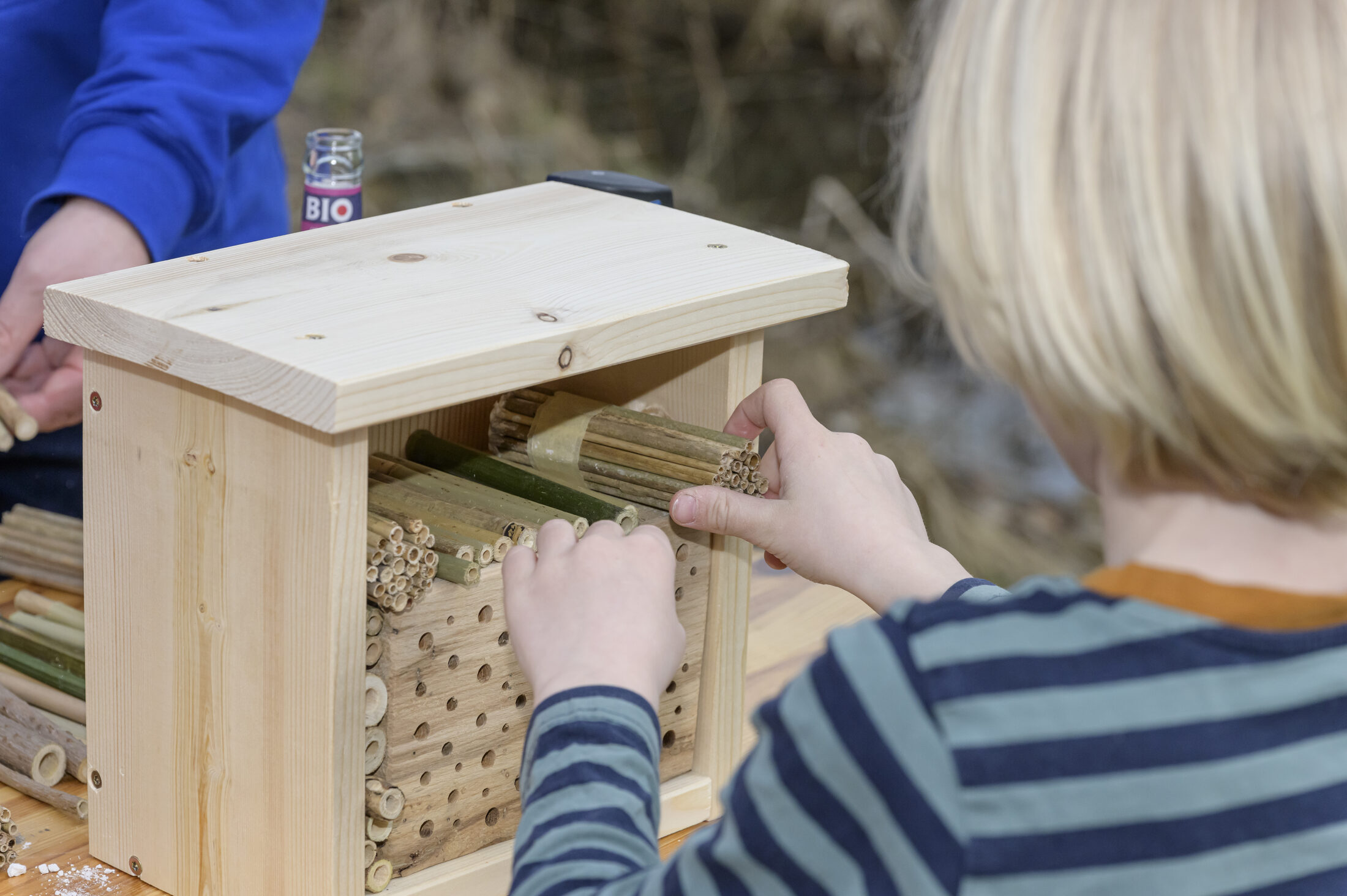 Ein Kind baut ein Insektenhotel. (Wird bei Klick vergrößert)