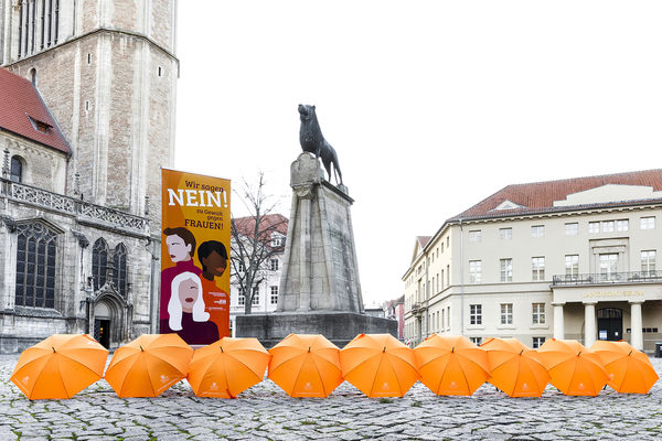 Burgplatz mit orangen Regenschirmen und Banner mit Aufschrift, Wir sagen Nein! zu Gewalt gegen Frauen!
