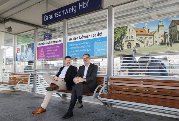 Oberbürgermeister Dr. Thorsten Kornblum und Gerold Leppa, Geschäftsführer des Stadtmarketings, präsentieren die neuen Beklebungen an den Sitzeinhausungen am Hauptbahnhof. (Wird bei Klick vergrößert)