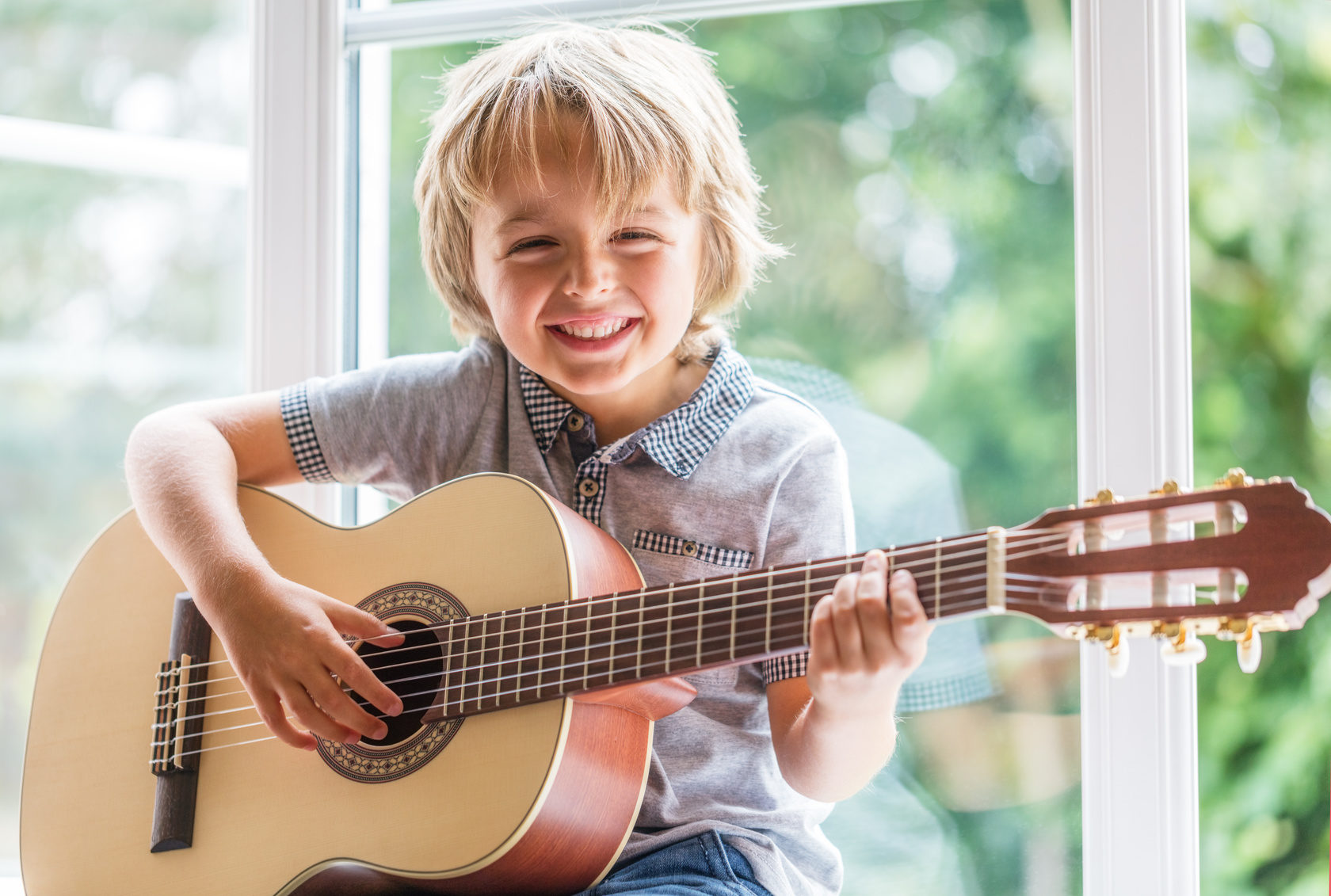 Happy smiling boy learning to play the acoustic guitar (Wird bei Klick vergrößert)