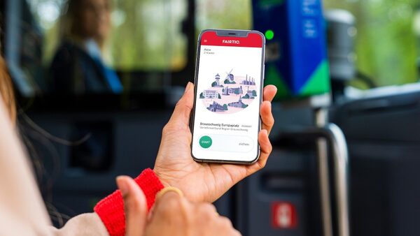Das Bild zeigt eine Hand, die ein Handy hält, auf dessen Bildschirm die FAIRTIQ-App geöffnet ist.
