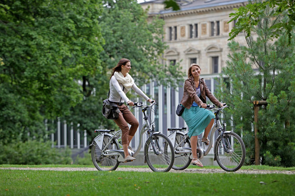 Zwei Frauen fahren mit dem Fahrrad durch den Park. (Wird bei Klick vergrößert)