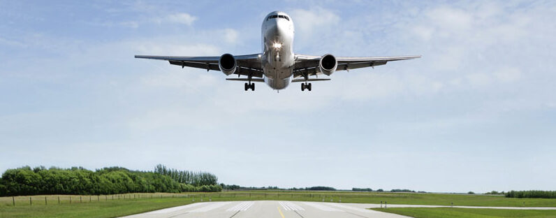 jet airplane landing on runway with bright sky