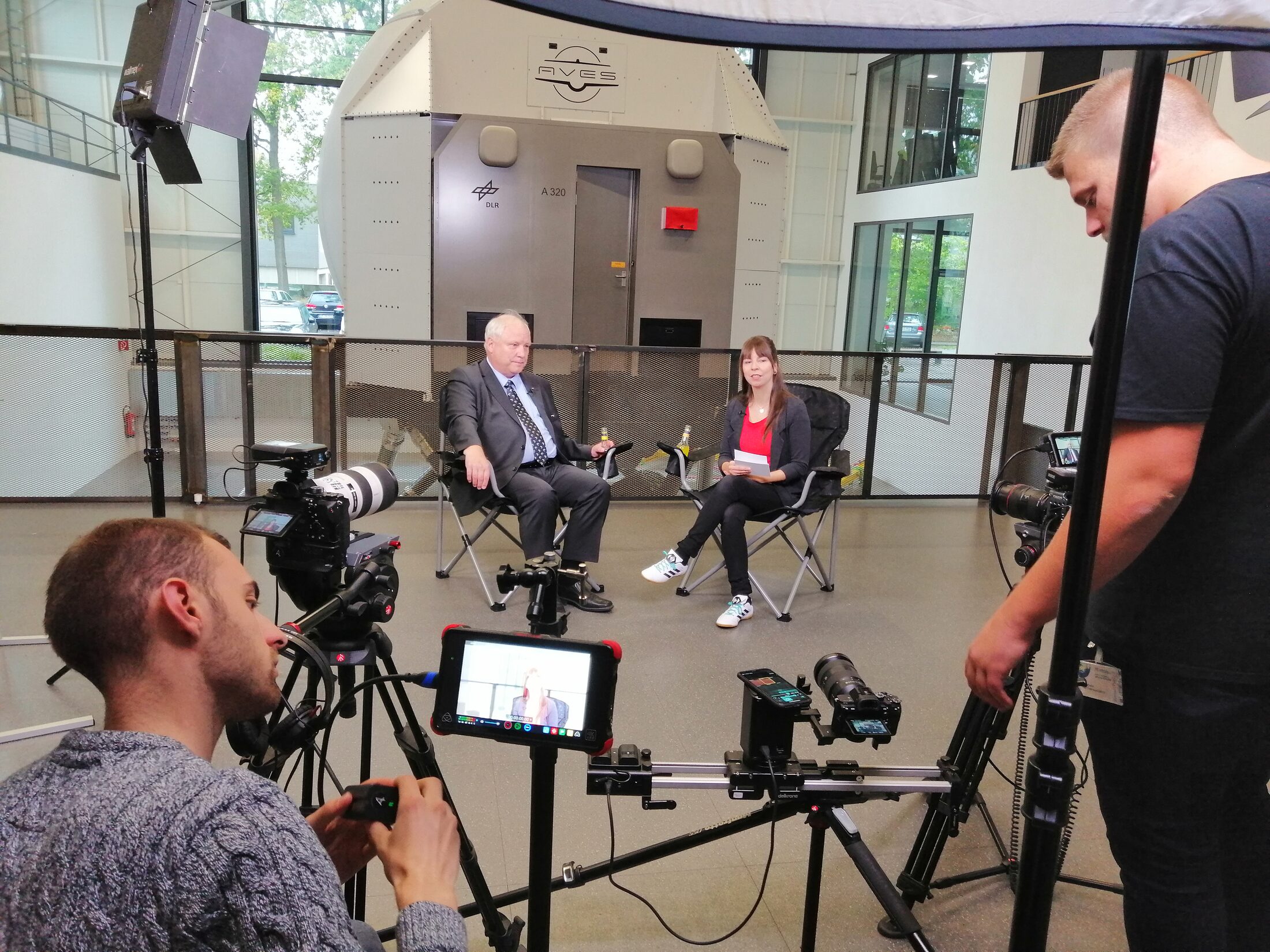 Prof. Dr. Joachim Block mit Moderatorin Jennifer Haacke bei den Dreharbeiten zum Video mit der Agentur Ausdruckslos. Im Hintergrund ist der Flugsimulator AVES im Einsatz. (Wird bei Klick vergrößert)