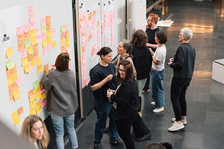 Menschen vor Whiteboard mit bunten Zetteln