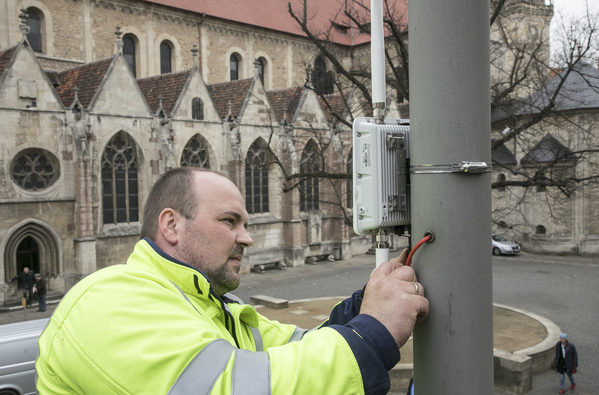 Am Braunschweiger Dom installiert ein Techniker von BS|Energy einen WLAN-Hotspot.