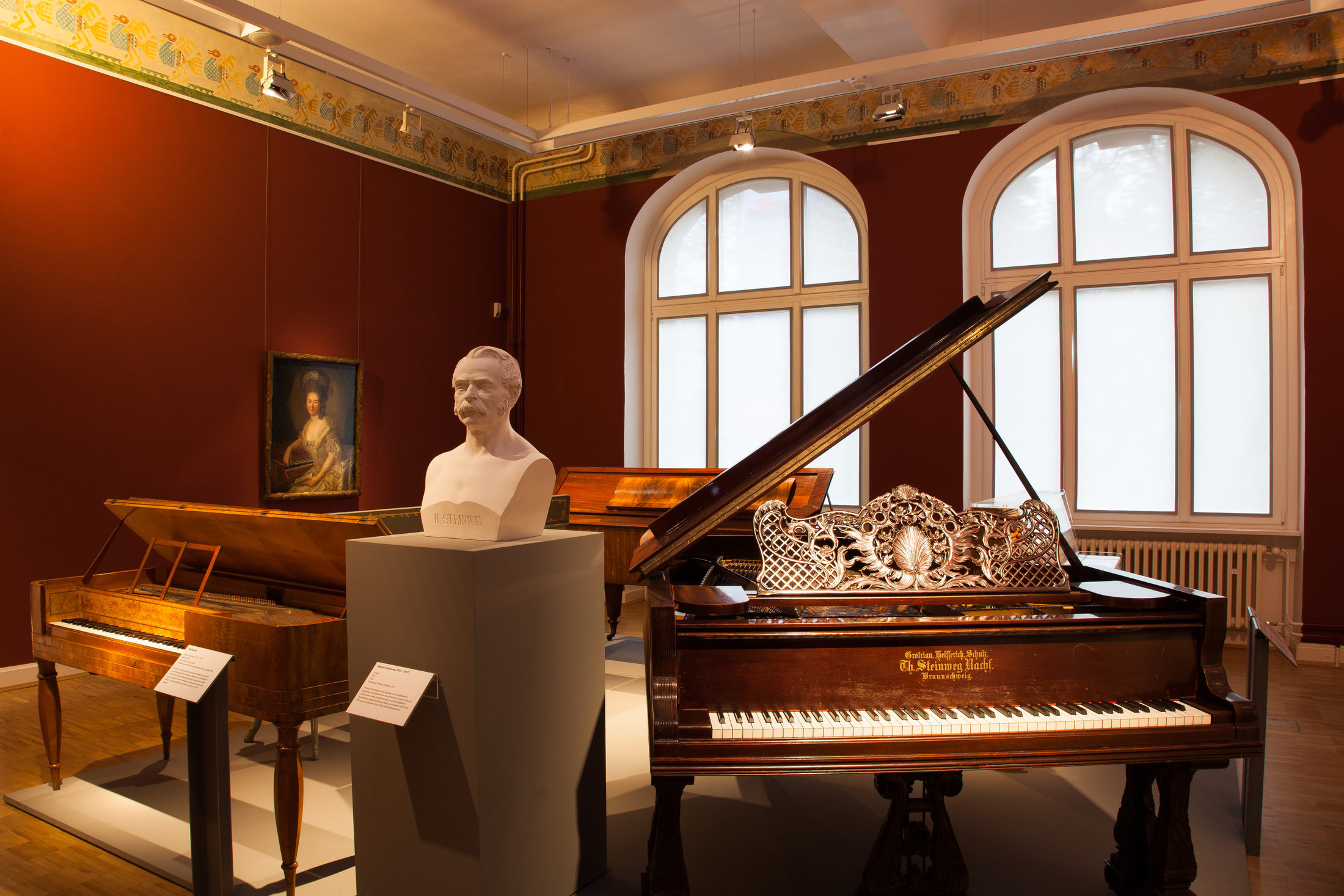 Einblick in die Ausstellungsräume des Hauses am Löwenwall mit Klavieren aus unterschiedlichen Zeiten, einer Gips-Büste und einem Gemälde (Wird bei Klick vergrößert)