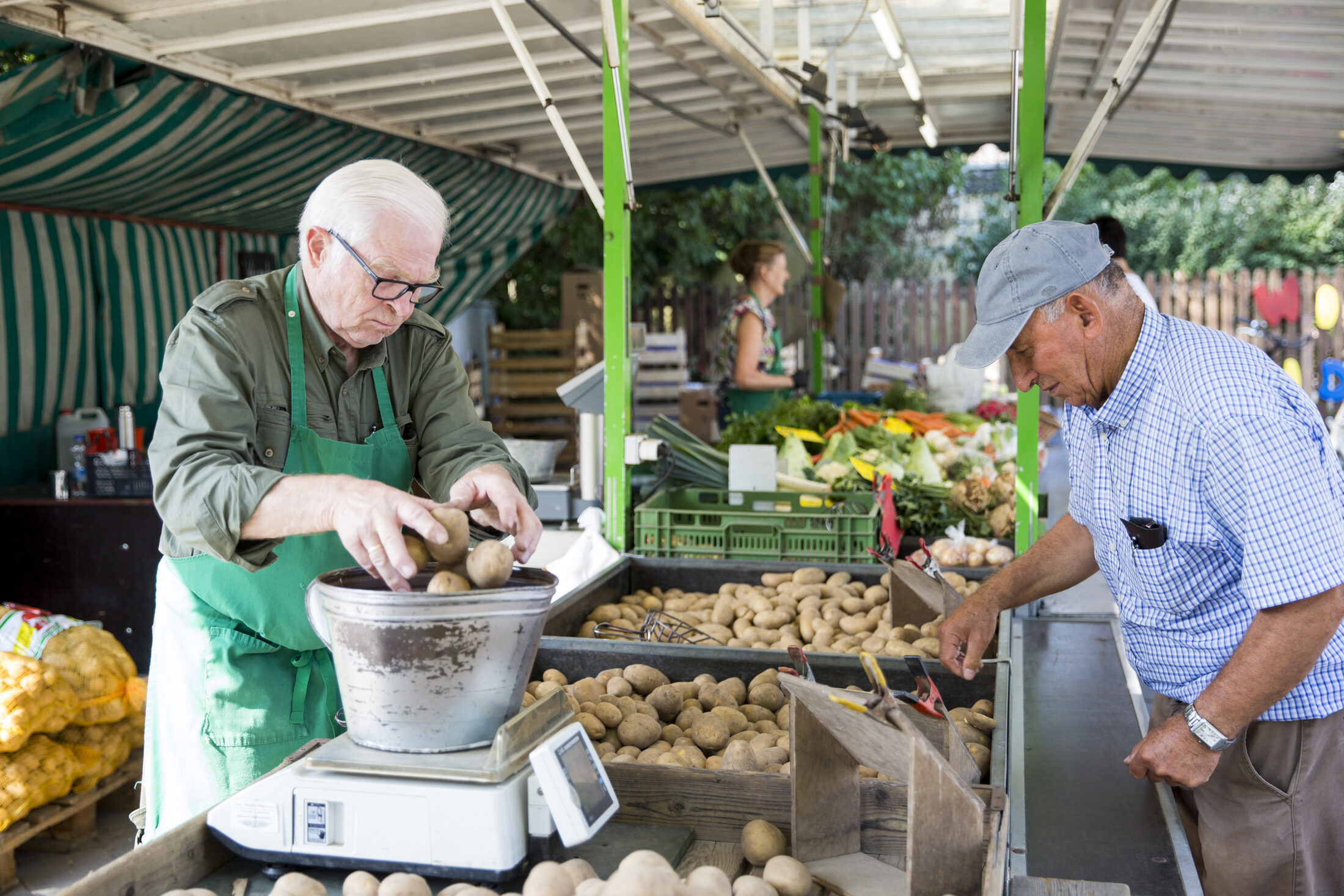 Einkauf von Kartoffeln am Marktstand. Abwiegen des Erdapfels (Wird bei Klick vergrößert)