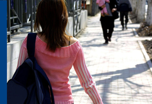 Rückenansicht einer Frau, die eine Straße entlanggeht
