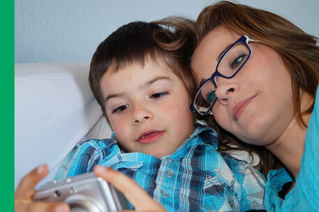 Mutter guckt gemeinsam mit ihrem etwas achtjährigen Sohn auf ein Foto-Display