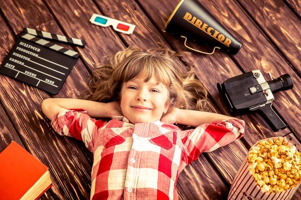 Child playing at home. Kid with vintage cinema objects. Entertainment concept. Top view