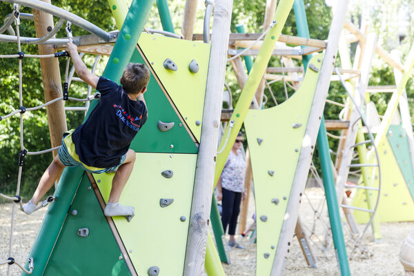 Ein Kind klettert an einem Spielgerät mit Kletterwand (Wird bei Klick vergrößert)