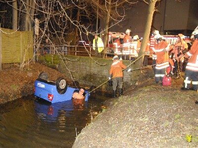 Ein Feuerwehrmann im Überlebensanzug befestigt die Seilwinde am Fahrzeug (Wird bei Klick vergrößert)