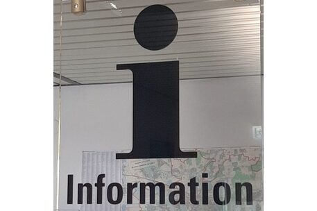 transparentes Schild "Information" mit einem Stadtplan im Hintergrund