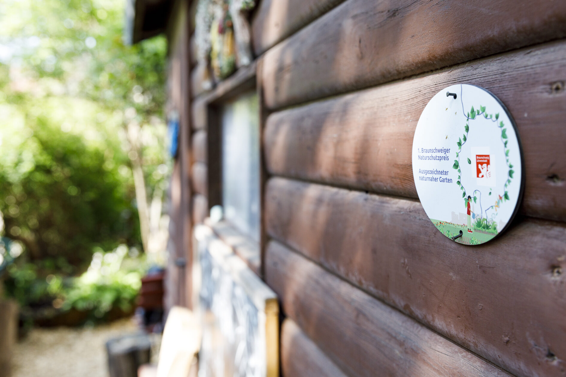 Plakette ausgezeichneter naturnaher Garten an einer Hauswand. (Wird bei Klick vergrößert)