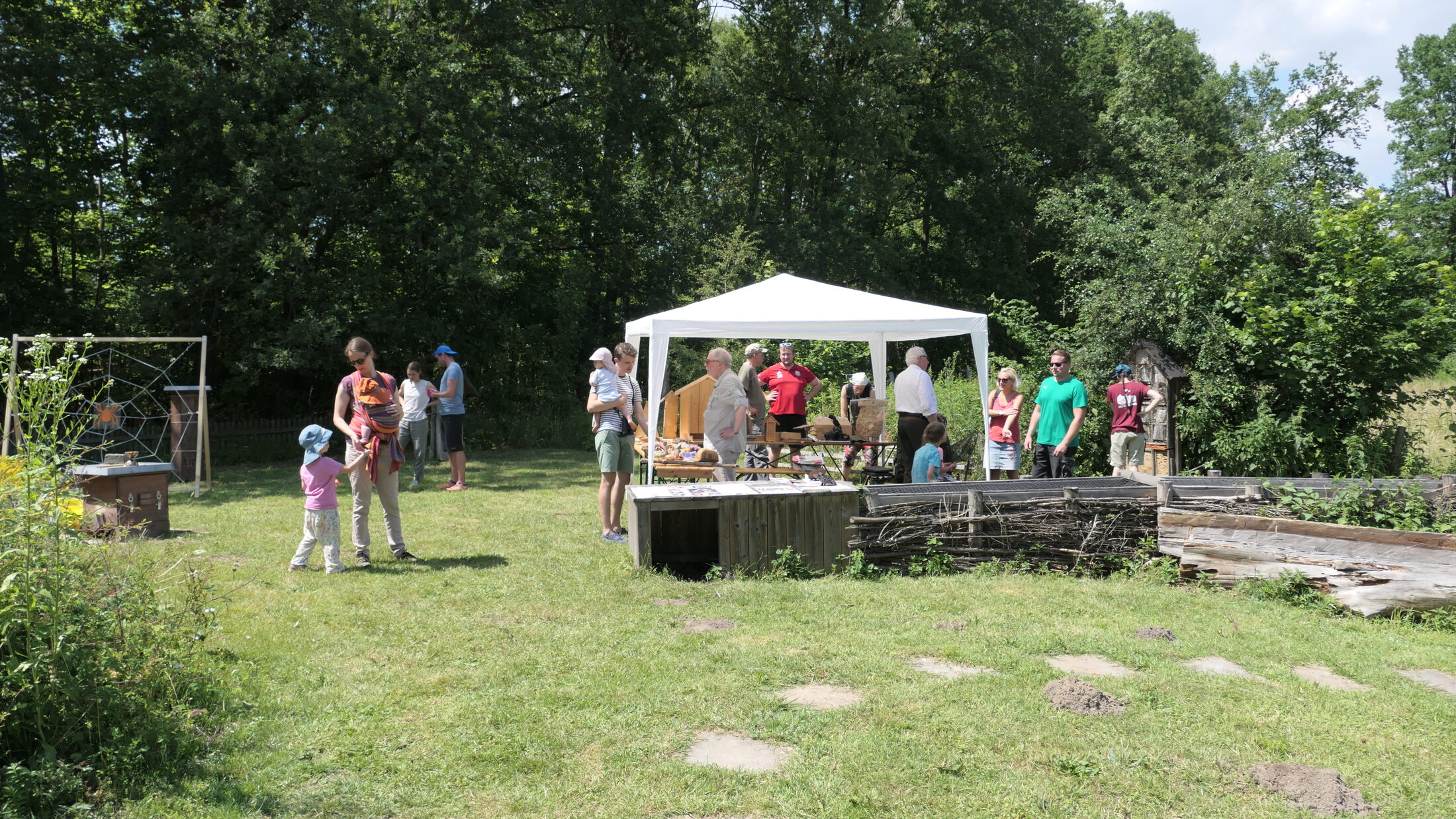 Um einen Pavillon auf einer Wiese stehen Familien mit Kindern. (Wird bei Klick vergrößert)