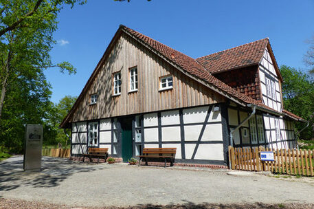 Vor einem historischen Fachwerkhaus stehen Bänke bei strahlendem Sonnenschein.