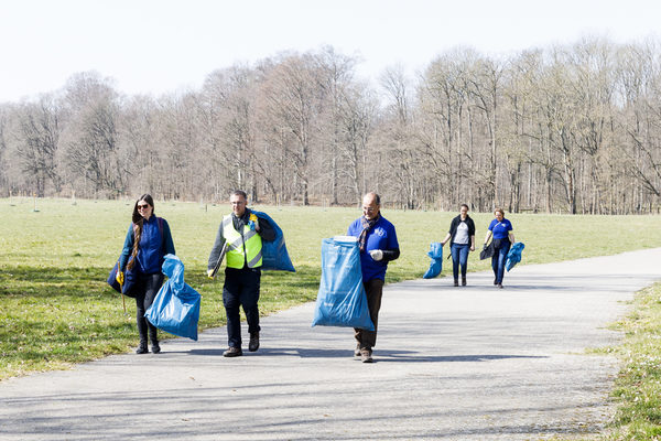 5 Helfende gehen beim Stadtputz über einen Weg und tragen blaue Säcke (Wird bei Klick vergrößert)