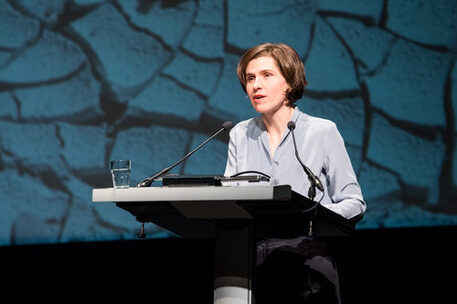 Gezeigt wird Judith Schalansky, Preisträgerin des Wilhelm Raabe-Literaturpreises 2018. Sie trägt ein blaues Oberteil und hat kürzere braune Haare. Auf dem Foto hält sie ihre Rede am Rednerpult mit Blick auf das Publikum