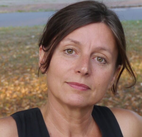 Susanne Maierhöfer steht draußen auf einer Wiese vor einer Straße, sieht in die Kamera, trägt einen Zopf (Wird bei Klick vergrößert)