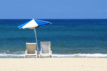 Sonnenstühle und Sonnenschirm am Strand