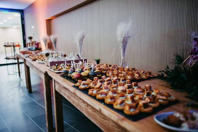 Fingerfood und Häppchen angerichtet auf langen Holztischen (Wird bei Klick vergrößert)