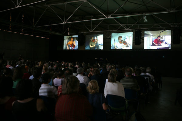 Die Bildschirme im Hangar 1 zeigen die vier Musiker in Nahaufnahme (Wird bei Klick vergrößert)