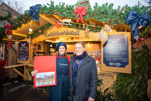 Knödel nach Geheimrezept: Standbetreiberin Carolin Pape freut sich über die Auszeichnung ihrer „Knödelwerkstatt“ zum schönsten Stand auf dem Braunschweiger Weihnachtsmarkt. Die Urkunde überreichte Wieslaw Puzia vom Arbeitsausschuss Tourismus Braunschweig e. V. (Wird bei Klick vergrößert)