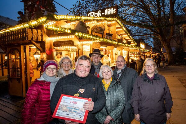 Der Gewinnerstand „Ross-Hütte“ von Stefan Franz (ganz vorne) ist in diesem Jahr bereits zum 40sten Mal Teil des Braunschweiger Weihnachtsmarktes. Es freuen sich die Jurymitglieder (v. l. n. r.) Dompredigerin Cornelia Götz (Braunschweiger Dom), Ingeborg Obi-Preuß (Braunschweiger Zeitung), Thomas Bronswyk (Schaustellerverband Braunschweig), Ulrike Neumann (Braunschweig Stadtmarketing GmbH), Karsten Ziaja (Arbeitsausschuss Tourismus Braunschweig e. V.) und Bezirksbürgermeisterin Jutta Plinke. Es fehlt: Jurymitglied Astrid Striese (Arbeitsausschuss Innenstadt Braunschweig e. V.). (Wird bei Klick vergrößert)