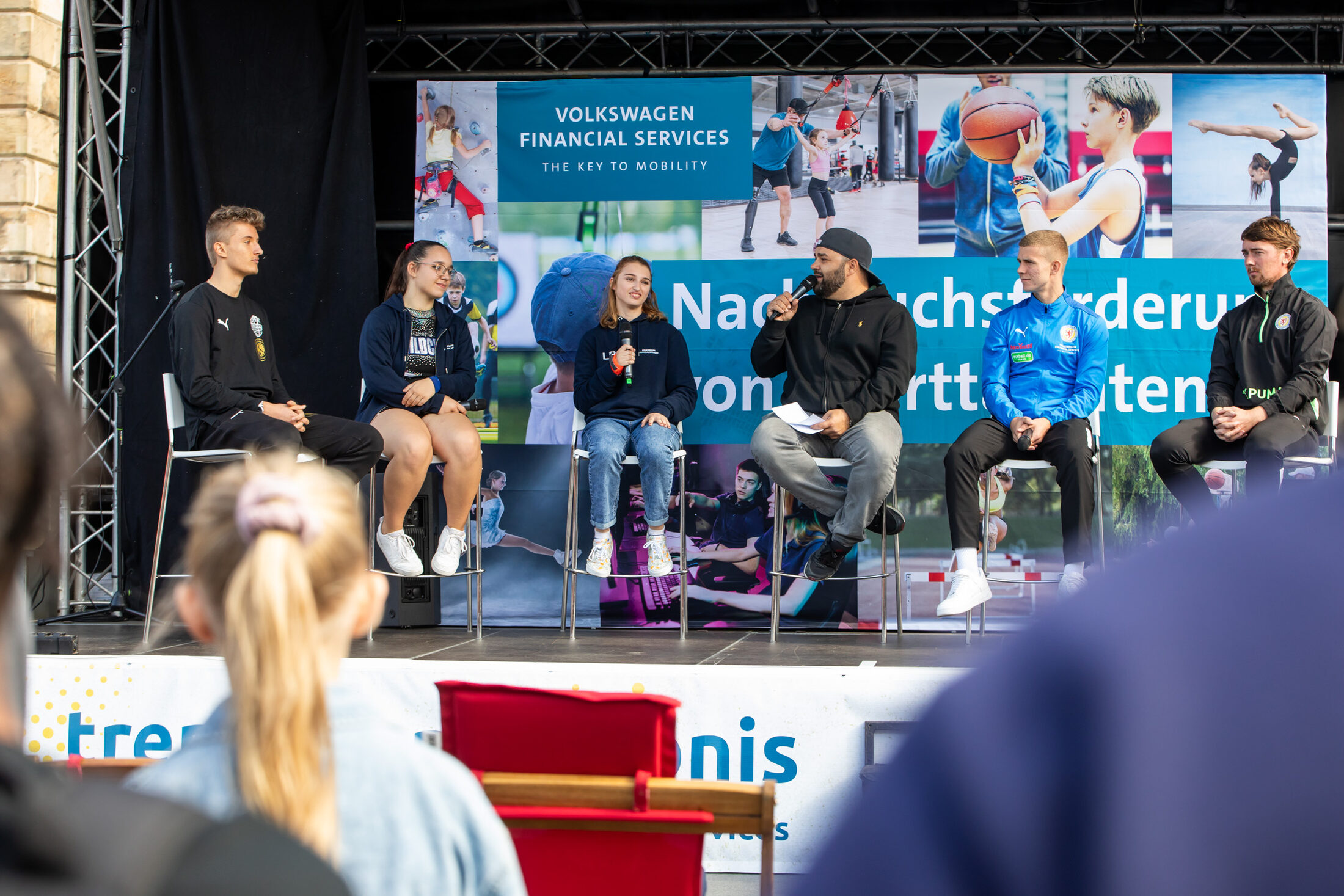 Auf der Bühne auf dem Schlossplatz erzählten die Nachwuchssportlerinnen und -sportler aus dem Förderprogramm von Volkswagen Financial Services über ihren Weg in den Profisport:(v. l. n. r.) Milio Stein (Basketball Löwen U19), Vivien Wieczorek (Wildcats MTV Braunschweig), Laura Burbulla (Para-Leichtathleletin), Moderator Chriz Rock, Maxim Root (U19-Spieler Eintracht Braunschweig) und Jonas Stephan (sportlicher Leiter des Nachwuchszentrums von Eintracht Braunschweig). (Wird bei Klick vergrößert)