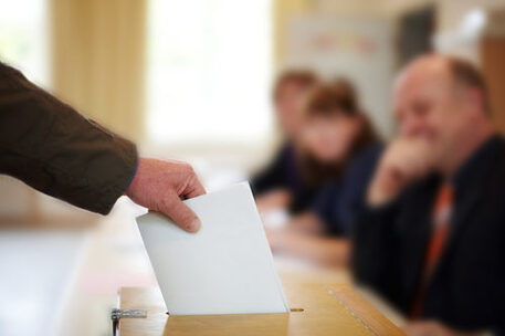 Stimmzettel wird in Wahlurne geworfen