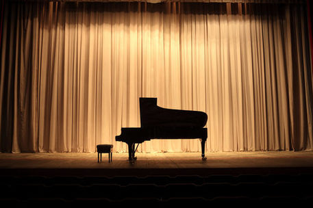 Klavier auf der Bühne vor nem gelben Vorhang