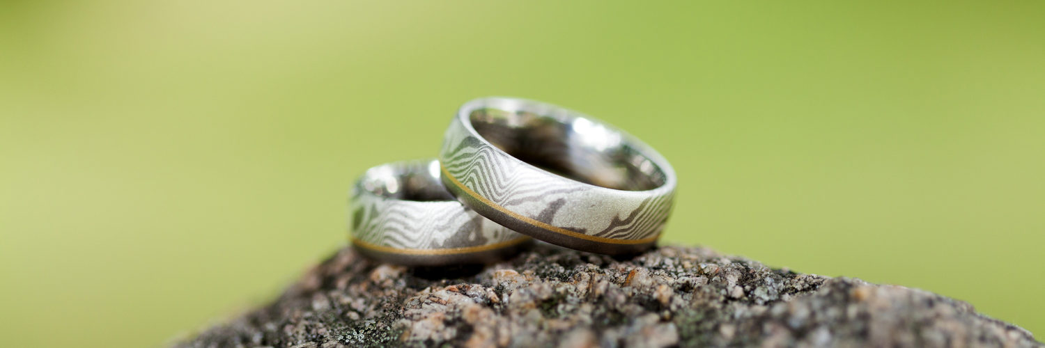 Zwei silberne Eheringe auf einem Stein