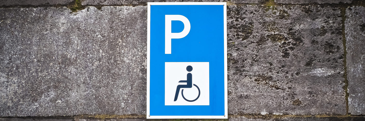 Parkplatzschild mit Behindertenzeichen an einer Wand