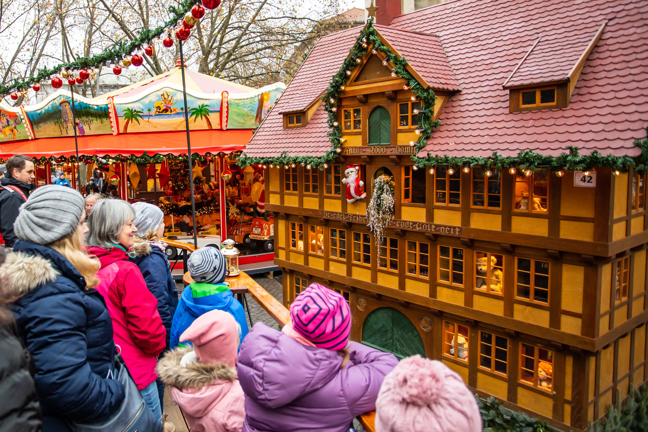 Kinder stehen draußen vor einem weihnachtlichen Puppentheater. (Wird bei Klick vergrößert)