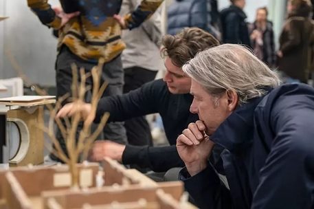 Das Bild zeigt zwei Männer, die ein Architekturmodell betrachten.