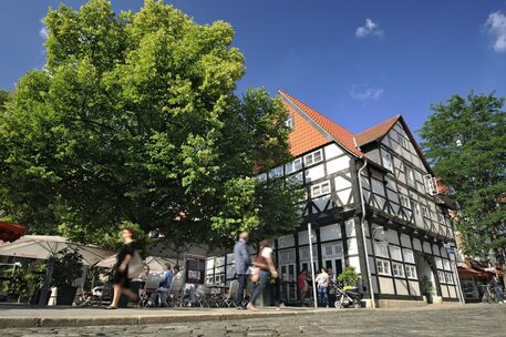 Das Bild zeigt Kopfsteinpflaster vor einem Fachwerkhaus an der Ecke des Magnikirchplatzes.