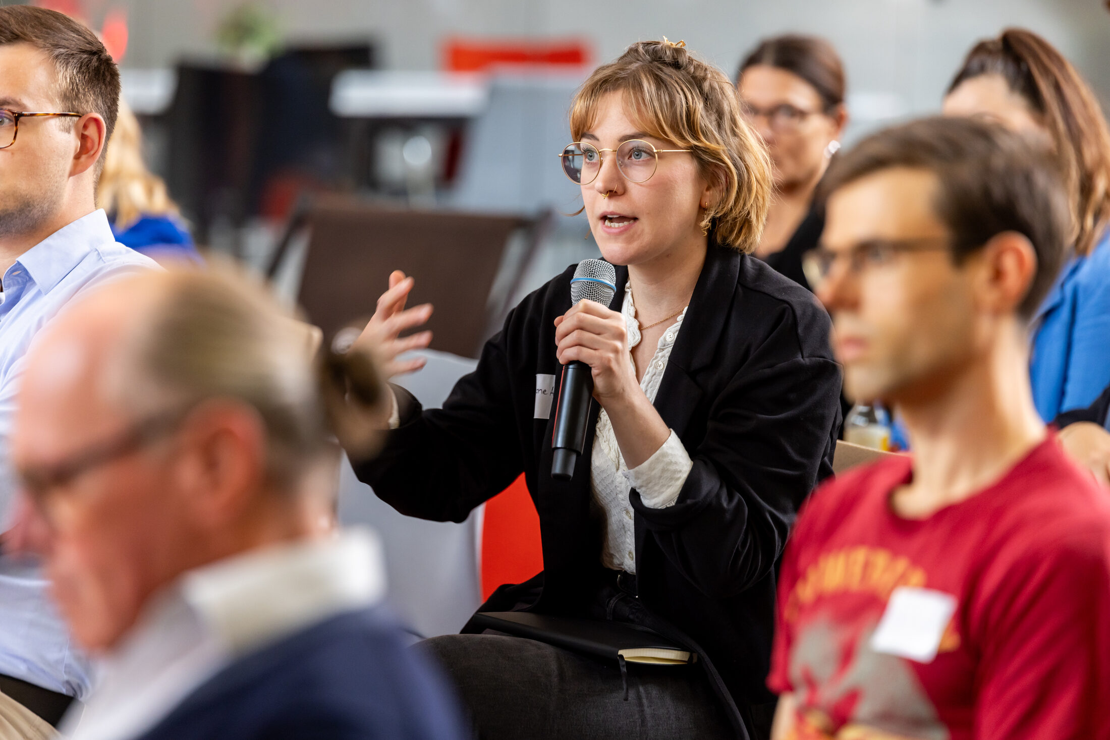Das Bild zeigt eine Frau, die in ein Mikrofon spricht. (Wird bei Klick vergrößert)