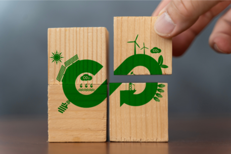 Das Bild zeigt vier Holzklötze auf denen ein grüner Pfeil gemalt ist. Der Pfeil stellt einen Kreislauf dar.